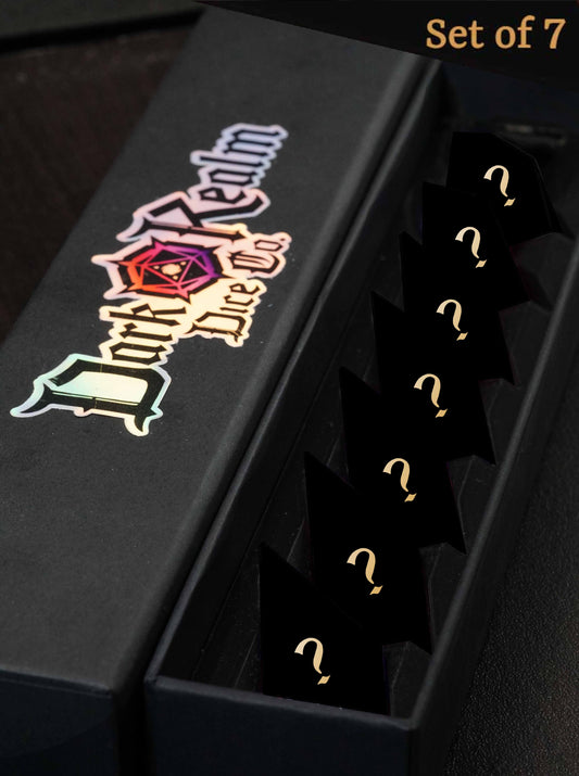 A dice box with a full 7 piece dice set of crystal shaped dice inside, obsured in appearance with "?"s above, signifying that they are random mystery dice that could be of any color. The words "DarkRealm Dice Co" is printed on the lid of the dice box, with a unique shaped spike D20 icon in the center of the logo.